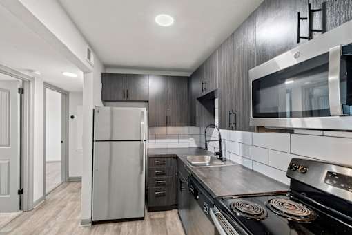 The Canvas Apartments modern kitchen with a stainless steel refrigerator and oven.