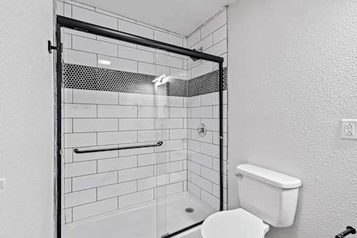 The Canvas Apartments Nashville bathroom with a white toilet and white tile shower.