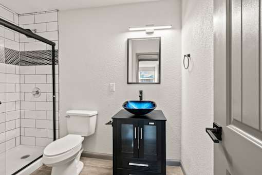 The Canvas Apartments Nashville bathroom with a white toilet, a black cabinet, and a mirror.