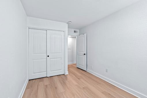 A white door is in a bedroom with wood flooring at The Canvas Apartments in East Nashville TN.