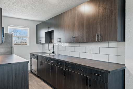 The Canvas Apartments in Nashville kitchen with dark wood cabinets and a white tile backsplash.