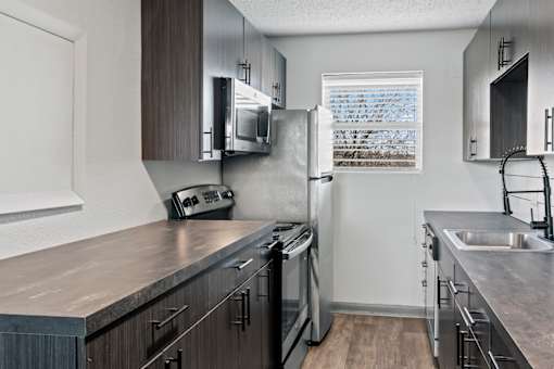 The Canvas Nashville apartments modern kitchen with dark wood cabinets and stainless steel appliances.