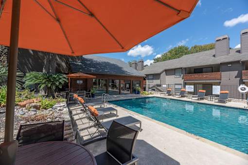 Fusion 35 pool area with a table and chairs under an orange umbrella.