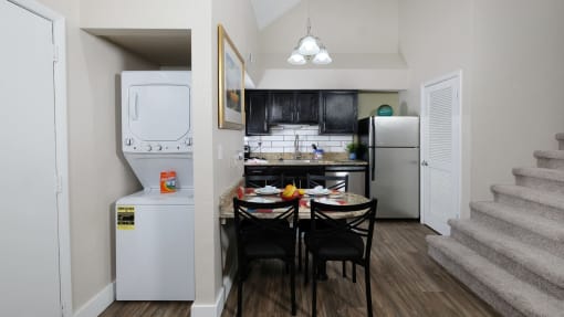 Fusion Orlando apartment kitchen with pantry and dinette next to in unit laundry washer and dryer and carpeted stairs leading up.