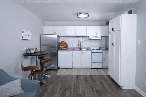 Kitchen in Fusion Fort Worth efficiency apartment in Haltom City with white cabinets, dishwasher, and electric stove and subway tile backsplash
