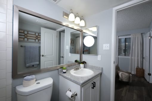 Fusion Fort Worth one bedroom apartment bathroom with single cabinet sink and chrome framed double mirror and medicine cabinet.