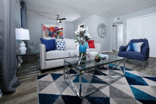 Living room in Stadium 700 apartments lofts in Arlington tx. Room is spacious with modern furniture and decor, ceiling fan, and luxury wood plank flooring.