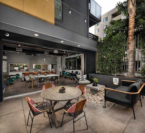 Fusion Encore Hollywood Apartments modern outdoor seating area with a wooden table surrounded by chairs.