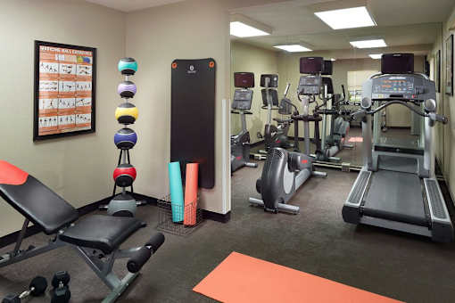 A fitness center with a variety of equipment including treadmills, weights, and exercise machines at Fusion Buckhead Apartments.