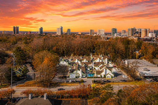 A sunset view of a city skyline with buildings and trees in the foreground at Fusion Buckhead Apartments Atlanta.