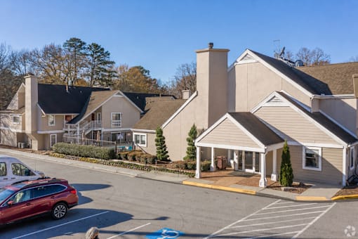 A red car is parked in a parking lot in front of a building at Fusion Buckhead Apartments.