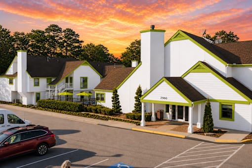 A white building with green trim and a red car parked in front at Fusion Buckhead Apartments