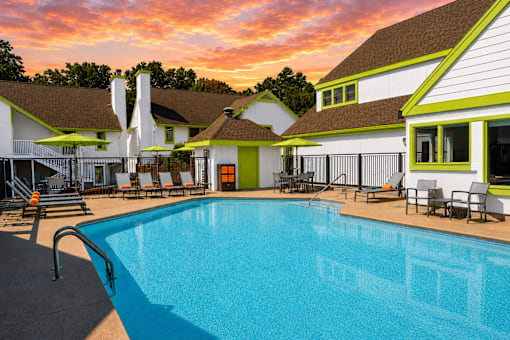 A swimming pool in front of Fusion Buckhead Apartments with a sunset in the background.