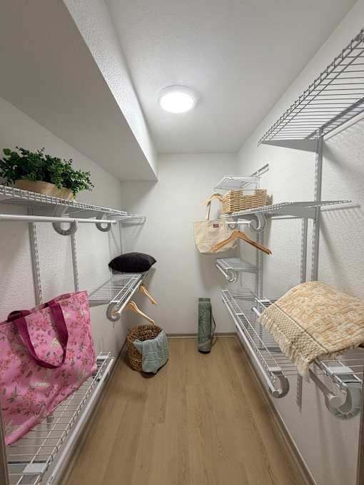 Fusion Crossroads walk-in closet with a pink bag hanging on the left.