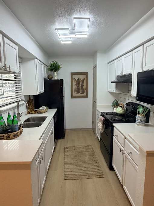 Fusion Crossroads kitchen with white cabinets and a black refrigerator.