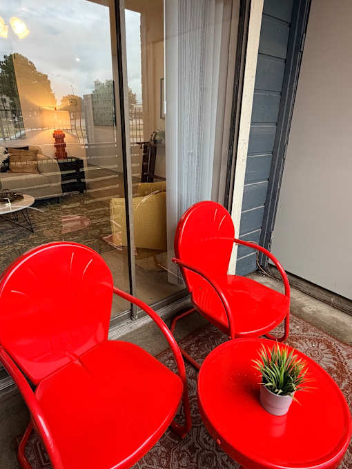 Fusion Crossroads patio with two red chairs and a small table with a plant on it.