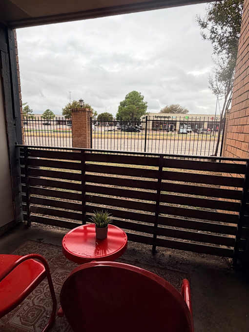 Fusion Crossroads balcony with a red table and chairs overlooking a parking lot.