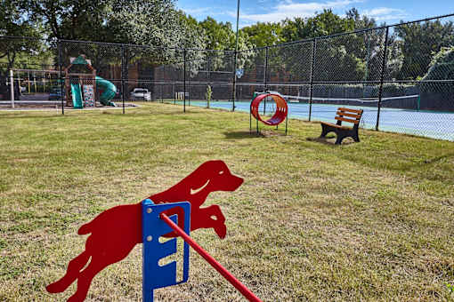 A dog jumping over a hurdle in a pet park.