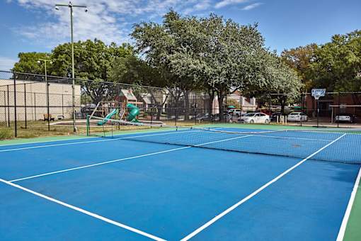 A blue sport court surrounded by a fence and trees at 1601 Eastchase Pkwy in Fort Worth, TX.