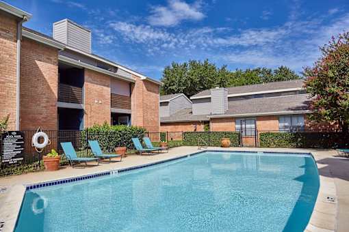 A swimming pool in front of a brick building with lounge chairs and plants around it at 1601 Eastchase Pkwy in Fort Worth, TX.