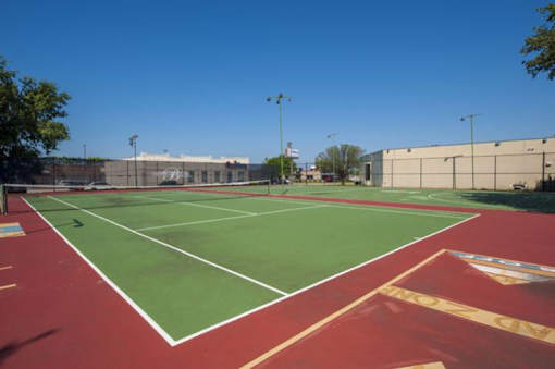 A tennis court with red and green surface and white lines at 1601 Eastchase Pkwy in Fort Worth, TX.