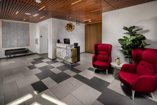 Fusion Encore Hollywood Apartments lobby area with a wooden ceiling and a checkered floor with two red chairs.