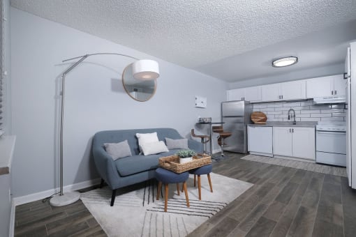 Open concept kitchen and living area in Fusion Fort Worth efficiency apartments Fort Worth TX with subway tile backsplash and modern lamp over a blue couch.