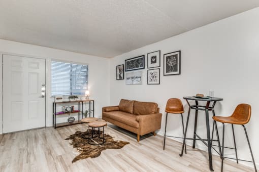 Fusion Fort Worth (previously Desert Sands Apartments) renovated apartment in Haltom City, TX living room with light wood plank flooring and camel colored midcentury modern furniture and decor.