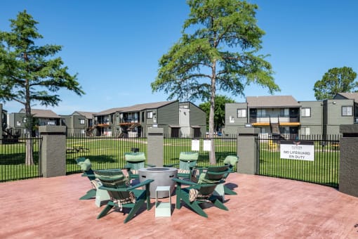 Outdoor seating at Fusion Fort Worth apartments in Haltom City, TX with green Adirondack chairs around a gas fire pit
