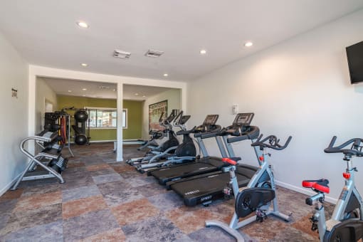 fitness center at Fusion Fort Worth apartments (previously Desert Sands) with cardio machines and large window