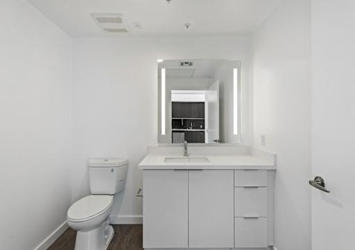 Fusion Hollywood white bathroom with a toilet, sink, and mirror.