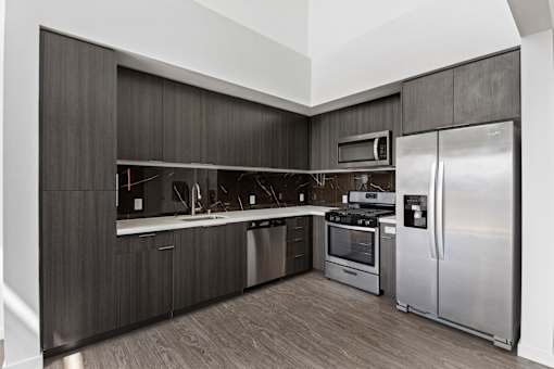 Fusion Hollywood apartments modern kitchen with dark wood cabinets and stainless steel appliances.