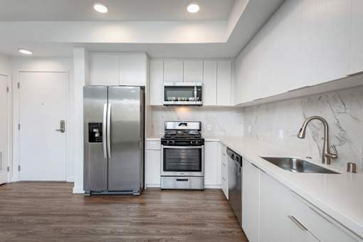Fusion Hollywood Apartments modern kitchen with a stainless steel refrigerator, stove, and oven.