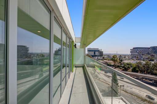 Fusion Hollywood private balcony with glass windows on the side and a view of the highway and buildings outside.