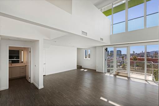Fusion Hollywood apartments spacious room with white walls and a view of the city through large windows.