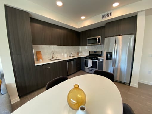 Fusion Hollywood Apartments with modern kitchen with a table and chairs in the foreground.