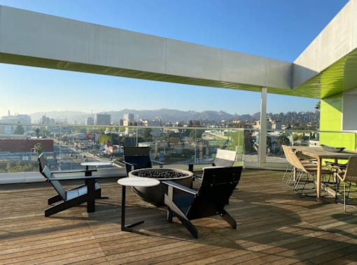 Fusion Hollywood rooftop deck with a table and chairs overlooking a cityscape.