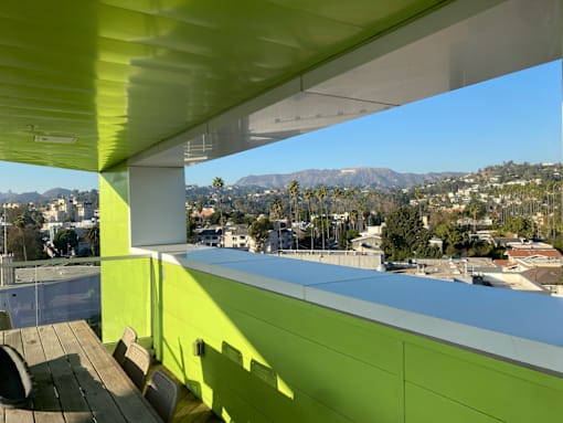 Fusion Hollywood (Alta Ink) Apartments green building with a view of the city and mountains.