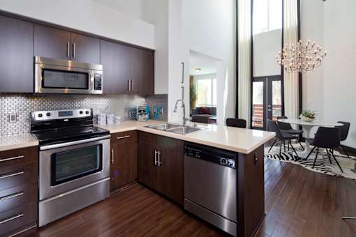 Fusion Encore Hollywood Apartments modern kitchen with dark wood cabinets and stainless steel appliances.