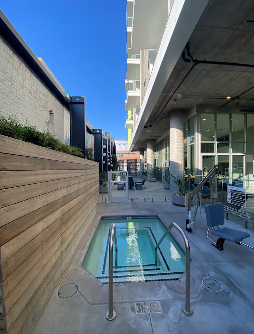 Fusion Hollywood apartments with hot tub jacuzzi spa with a metal railing is surrounded by a wooden fence.