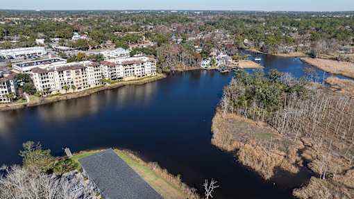 A river flows through a city with apartment buildings on one side and a grassy area on the other at Mandarin Bay Apartments