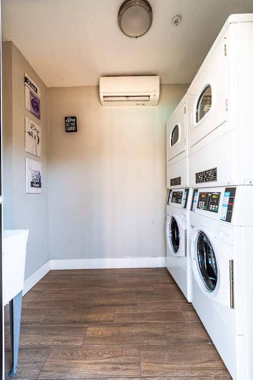 A row of white front load washing machines in a laundry facility at Mandarin Bay Apartments