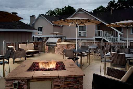 A patio with a fire pit and chairs.