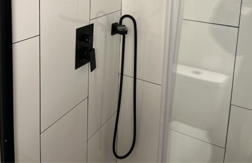 The Retreat at Indian Lake - Renovated Studio Shower with White Tile and Black Hardware