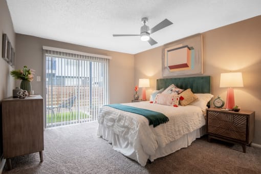 Large bedroom in the Stadium 700 luxury apartments in Arlington, TX with queen bed, ceiling fan, and large sliding glass door