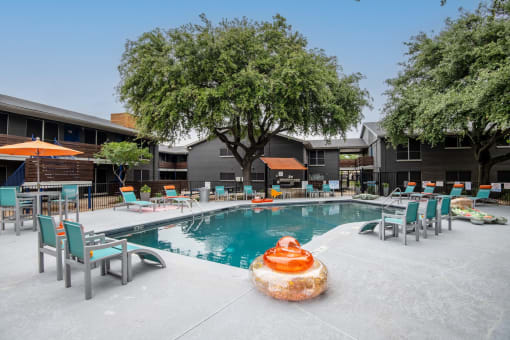 community swimming pool at Stadium 700 apartments in Arlington, TX with patio furniture and large trees.