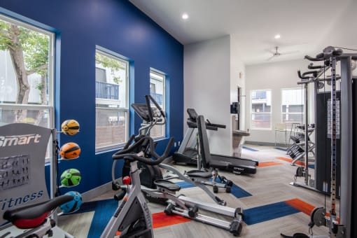 Fitness center at Stadium 700 Apartments in Arlington, TX with cardio machines, weights, and exercise balls