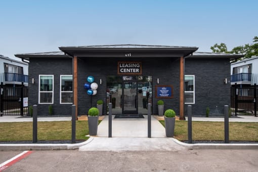 Leasing Center at Stadium 700 Apartments in Arlington, TX - a grey brick building with dark stained wood columns for awning