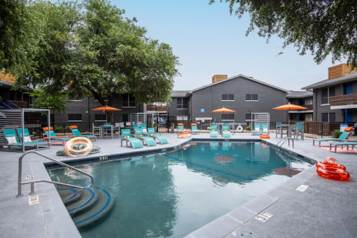Large community pool at Stadium 700 apartments in Arlington, TX with lounge chairs and inflatable pool rings