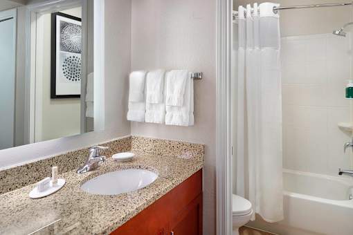 A bathroom with a white tub, sink, and towel at Fusion Buckhead Apartments.
